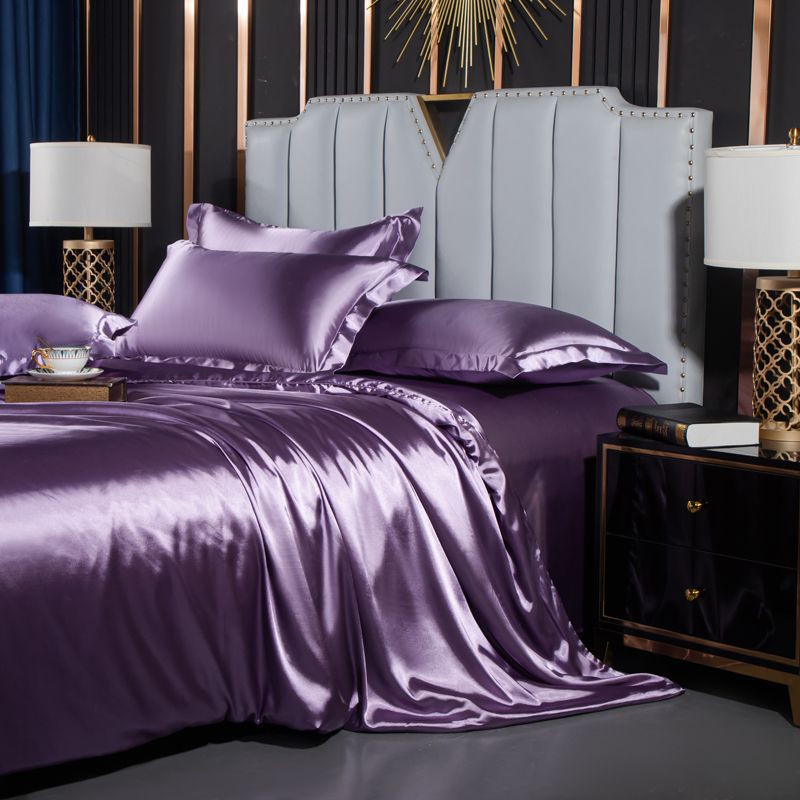 moregrowth101 Washed Silk Four-Piece Bedding Set in purple displayed on a stylish bed with elegant headboard and lamps.